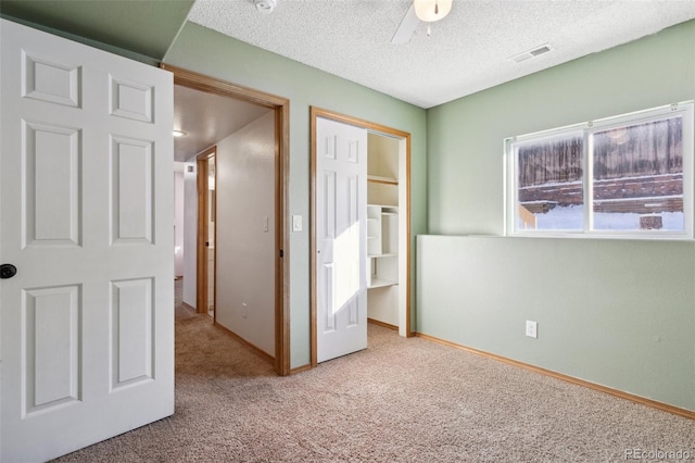 unfurnished bedroom with light carpet, a textured ceiling, a closet, and ceiling fan