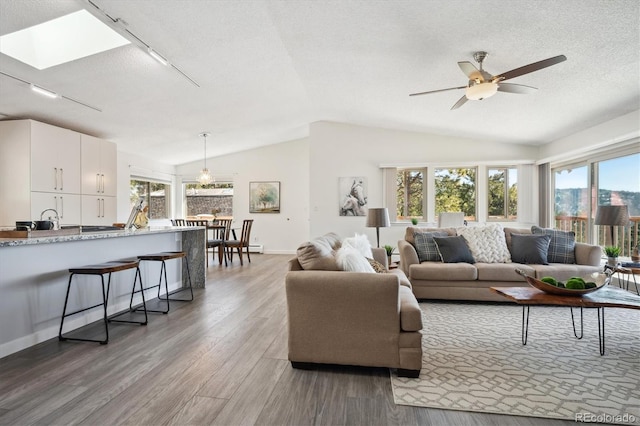 8045 S Wagon Wheel Rd, Morrison, CO 80465 - living area featuring vaulted ceiling, plenty of natural light, wood finished floors, track lighting, and ceiling fan