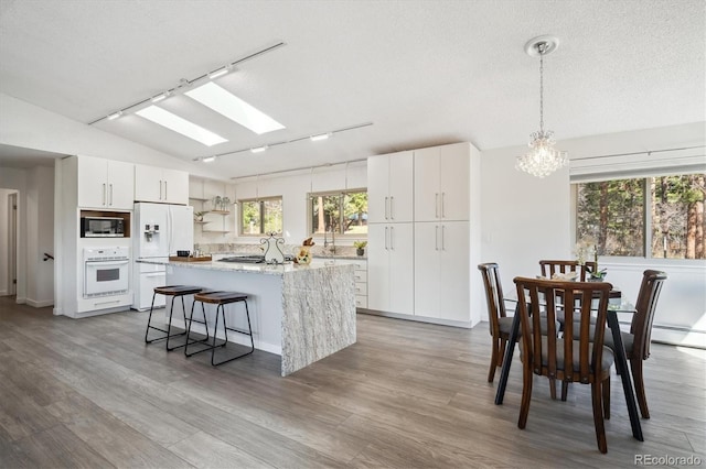 8045 S Wagon Wheel Rd, Morrison, CO 80465 - kitchen featuring white appliances, a chandelier, lofted ceiling, track lighting, and open shelves