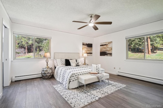 8045 S Wagon Wheel Rd, Morrison, CO 80465 - bedroom with a baseboard radiator, a textured ceiling, wood finished floors, a baseboard heating unit, and a ceiling fan