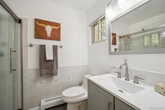 8045 S Wagon Wheel Rd, Morrison, CO 80465 - bathroom with a baseboard radiator, a shower stall, tile walls, vanity, and toilet
