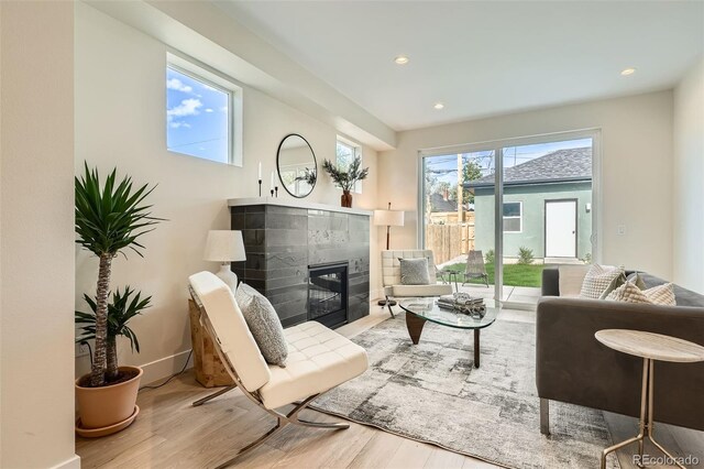 living room with wood finished floors, a tile fireplace, recessed lighting, and baseboards