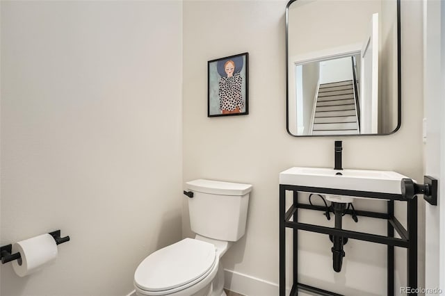 half bath with baseboards and toilet