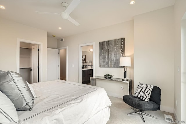 bedroom featuring recessed lighting, light carpet, connected bathroom, a ceiling fan, and a walk in closet