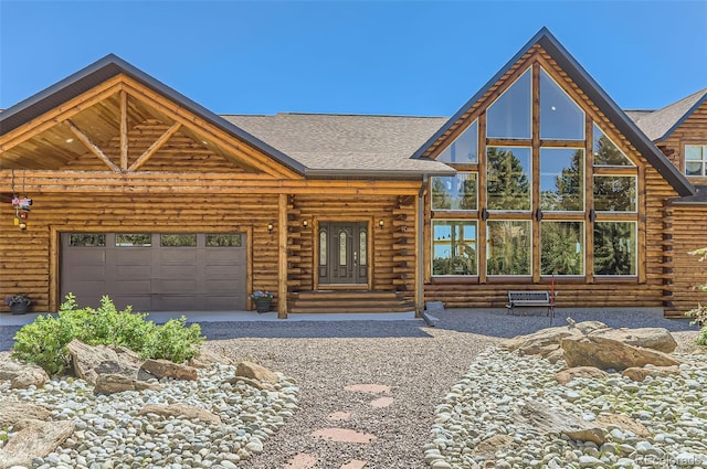 log home featuring a garage, a shingled roof, and log exterior