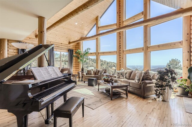 living room featuring rustic walls, hardwood / wood-style flooring, high vaulted ceiling, and beam ceiling