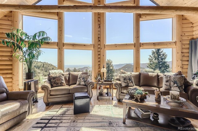 sunroom featuring a mountain view and vaulted ceiling with beams