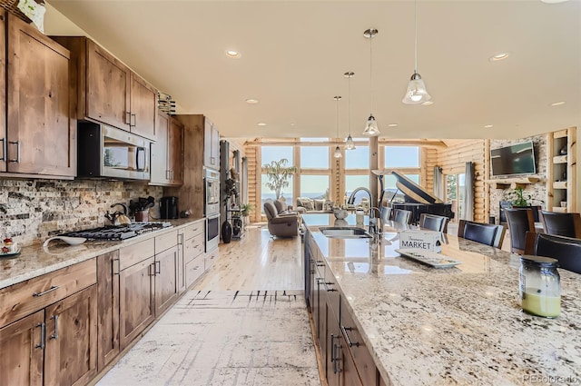 kitchen featuring appliances with stainless steel finishes, light stone counters, sink, and a healthy amount of sunlight