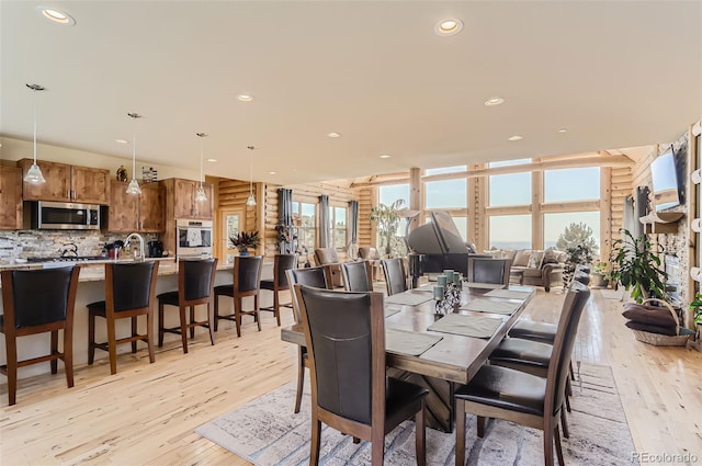 dining room with light wood-style floors, rustic walls, and recessed lighting