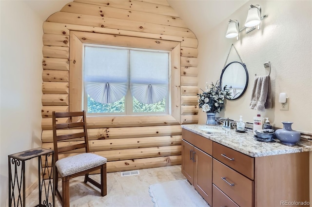 bathroom with rustic walls, tile patterned flooring, vanity, and vaulted ceiling