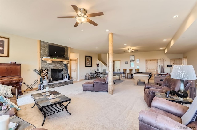 carpeted living room featuring ceiling fan and a stone fireplace