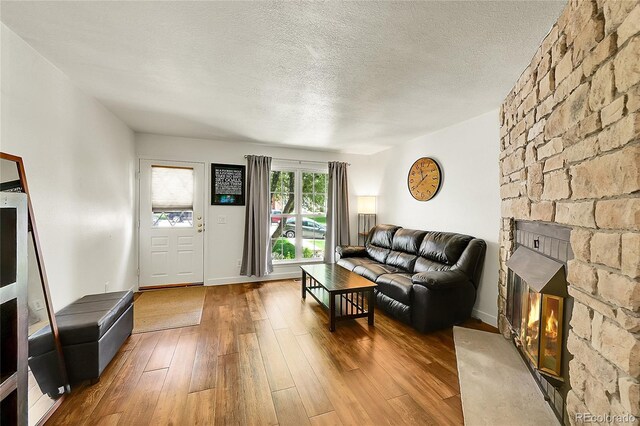 6765 S Independence St, Littleton, CO 80128 - living area featuring a fireplace, wood-type flooring, a textured ceiling, and baseboards