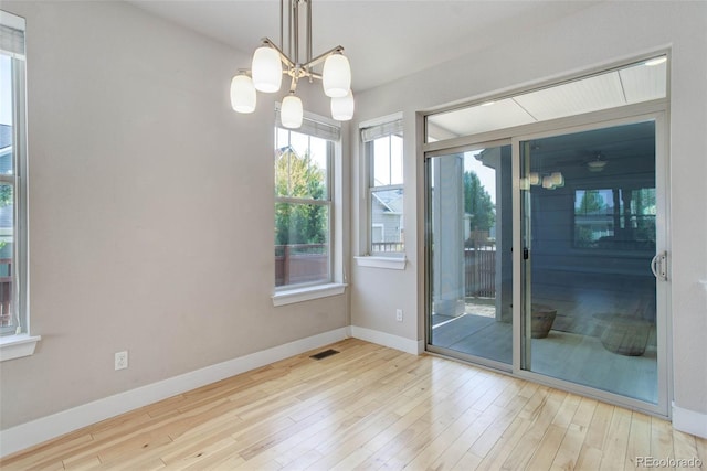 unfurnished room featuring light wood-type flooring and an inviting chandelier