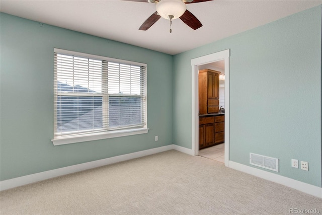 spare room featuring ceiling fan and light colored carpet