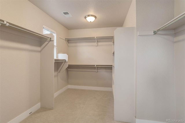 walk in closet featuring light colored carpet