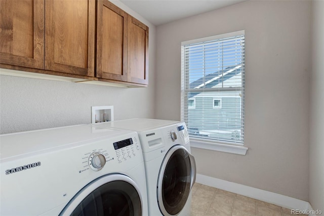 clothes washing area with independent washer and dryer, light tile patterned flooring, and cabinets