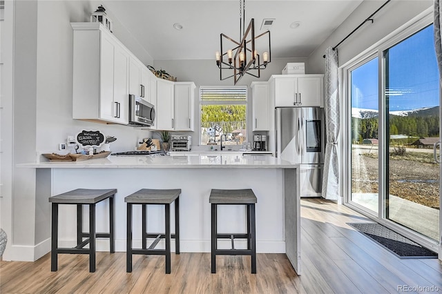 499 Silver Creek Rd, Idaho Springs, CO 80452 - kitchen with appliances with stainless steel finishes, a peninsula, plenty of natural light, and white cabinetry