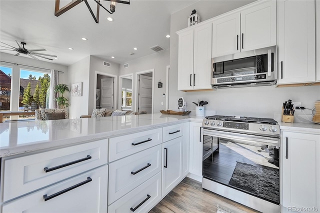 499 Silver Creek Rd, Idaho Springs, CO 80452 - kitchen featuring appliances with stainless steel finishes, light stone countertops, recessed lighting, white cabinets, and a peninsula