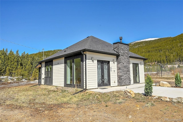 499 Silver Creek Rd, Idaho Springs, CO 80452 - rear view of house featuring a chimney, a view of trees, and french doors