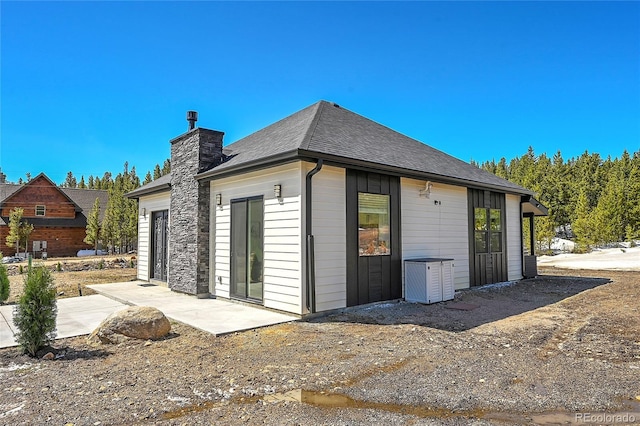 499 Silver Creek Rd, Idaho Springs, CO 80452 - rear view of house featuring cooling unit, a chimney, and a shingled roof