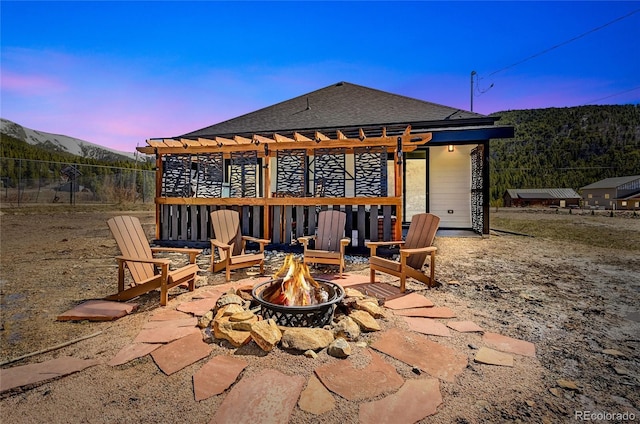 499 Silver Creek Rd, Idaho Springs, CO 80452 - patio terrace at dusk with an outdoor fire pit, a pergola, and a mountain view