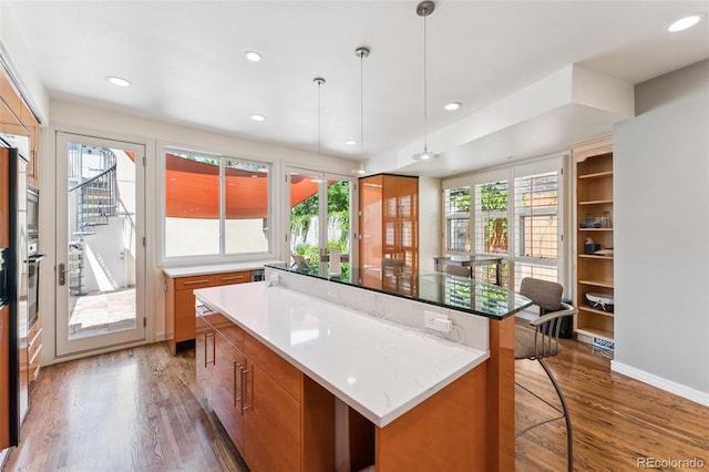 461 Fillmore St, Denver, CO 80206 - kitchen featuring wood finished floors, a kitchen island, brown cabinets, recessed lighting, and hanging light fixtures