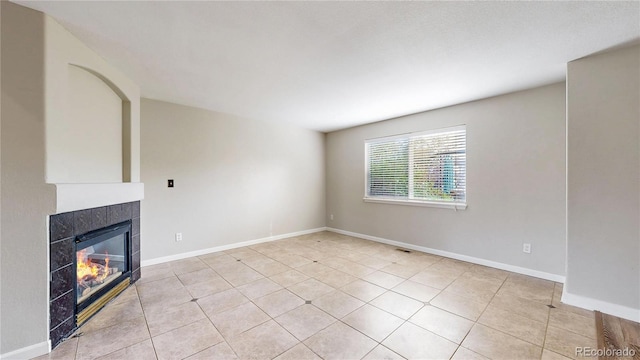 unfurnished living room with baseboards, a fireplace, and light tile patterned flooring