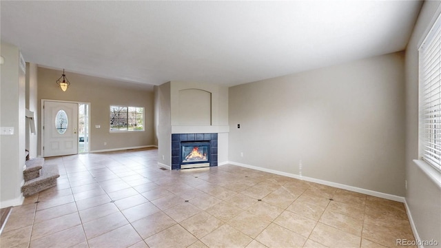 unfurnished living room featuring light tile patterned floors, baseboards, and a fireplace