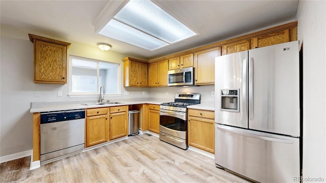 kitchen featuring light countertops, appliances with stainless steel finishes, light wood-style floors, and a sink