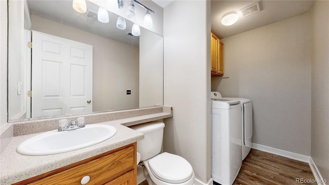 half bathroom featuring toilet, baseboards, vanity, wood finished floors, and separate washer and dryer