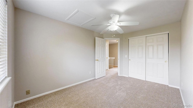unfurnished bedroom with carpet flooring, a ceiling fan, a closet, attic access, and baseboards