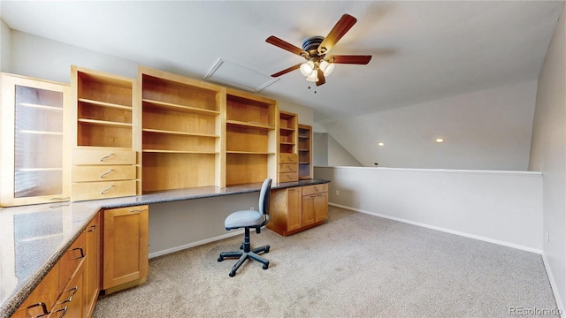 unfurnished office featuring a ceiling fan, baseboards, light colored carpet, built in study area, and lofted ceiling
