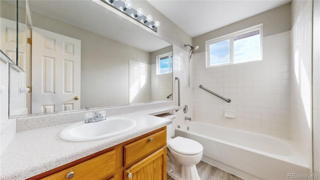 bathroom with toilet, wood finished floors, vanity, and washtub / shower combination