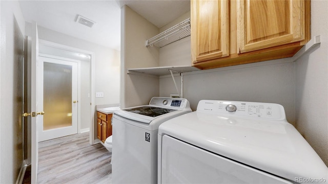 washroom with light wood-type flooring, laundry area, washing machine and dryer, and visible vents