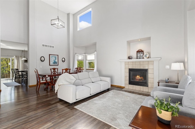 living room with wood finished floors, plenty of natural light, a high ceiling, and a tiled fireplace