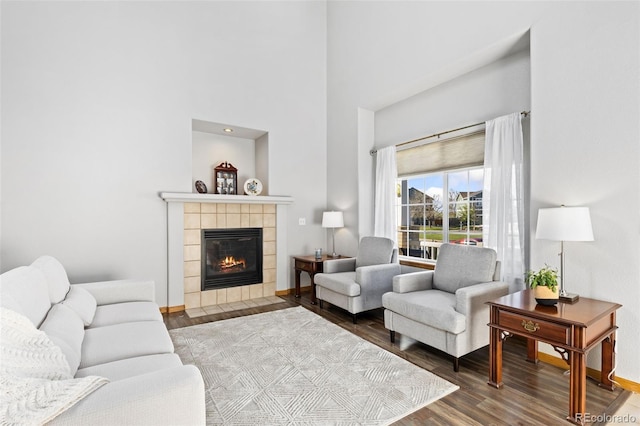 living area with wood finished floors, a fireplace, a high ceiling, and baseboards