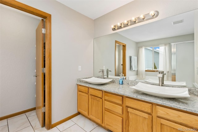 bathroom with double vanity, a shower with shower door, tile patterned floors, and baseboards