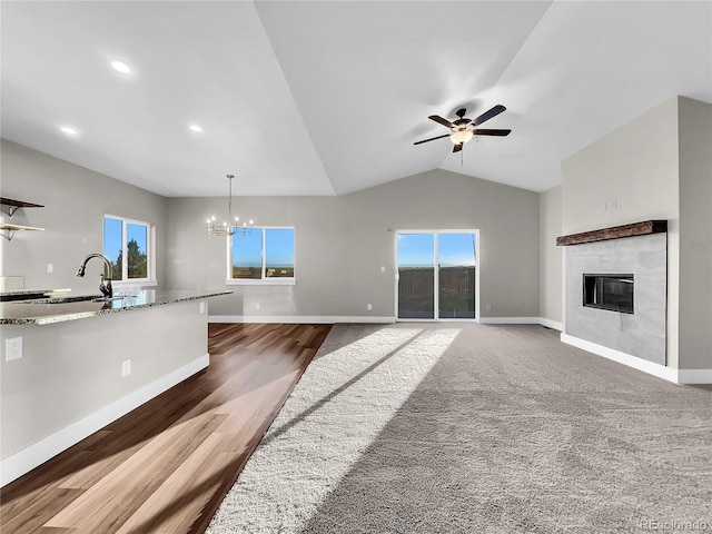 living room featuring ceiling fan with notable chandelier, dark hardwood / wood-style floors, lofted ceiling, and a fireplace