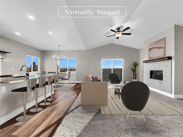 living room featuring a tile fireplace, ceiling fan with notable chandelier, plenty of natural light, and lofted ceiling