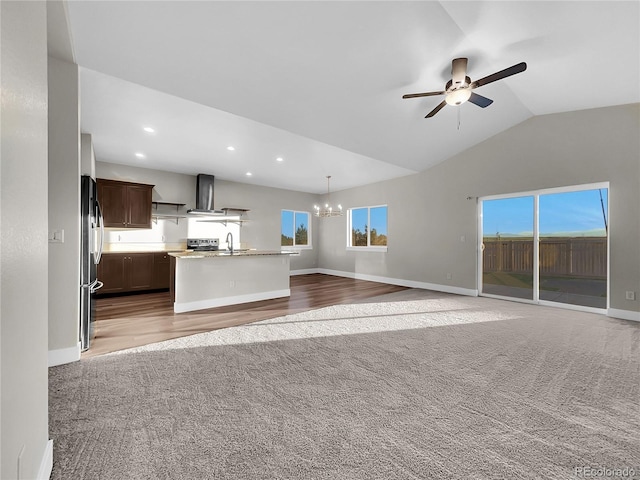 unfurnished living room featuring dark colored carpet, ceiling fan with notable chandelier, vaulted ceiling, and sink