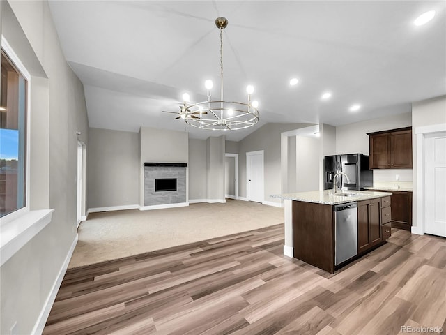 kitchen with a stone fireplace, stainless steel dishwasher, a notable chandelier, black fridge with ice dispenser, and dark brown cabinets