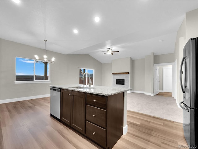 kitchen with pendant lighting, ceiling fan with notable chandelier, sink, light stone countertops, and stainless steel appliances