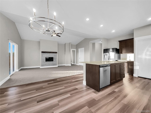 kitchen featuring a fireplace, a kitchen island with sink, dishwasher, hanging light fixtures, and lofted ceiling