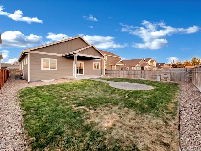 back of property with central AC, a patio area, and a lawn