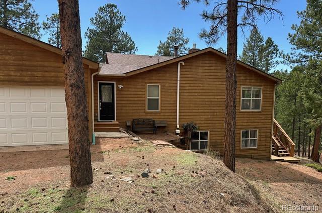 14694 Crooked Trail Rd, Woodland Park, CO 80863 - rear view of house featuring an attached garage, stairway, and entry steps