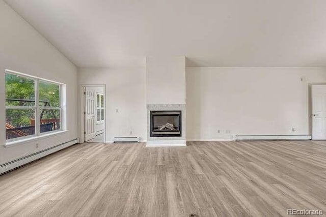 14694 Crooked Trail Rd, Woodland Park, CO 80863 - unfurnished living room with a baseboard radiator, wood finished floors, a glass covered fireplace, baseboard heating, and baseboards