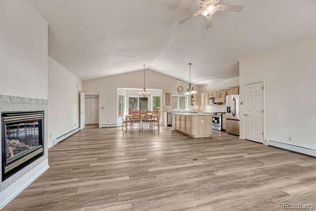 14694 Crooked Trail Rd, Woodland Park, CO 80863 - unfurnished living room featuring vaulted ceiling, wood finished floors, a ceiling fan, a tile fireplace, and a chandelier