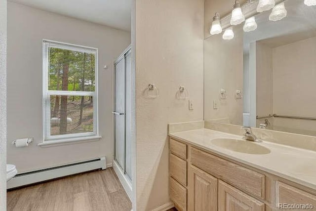 14694 Crooked Trail Rd, Woodland Park, CO 80863 - full bath featuring a baseboard radiator, vanity, wood finished floors, a shower with door, and baseboards