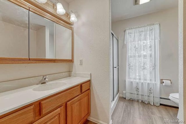 14694 Crooked Trail Rd, Woodland Park, CO 80863 - bathroom with vanity, toilet, a shower stall, wood finished floors, and a baseboard heating unit