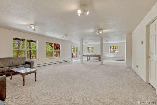 14694 Crooked Trail Rd, Woodland Park, CO 80863 - unfurnished living room featuring a baseboard heating unit, healthy amount of natural light, light carpet, a textured ceiling, and baseboards
